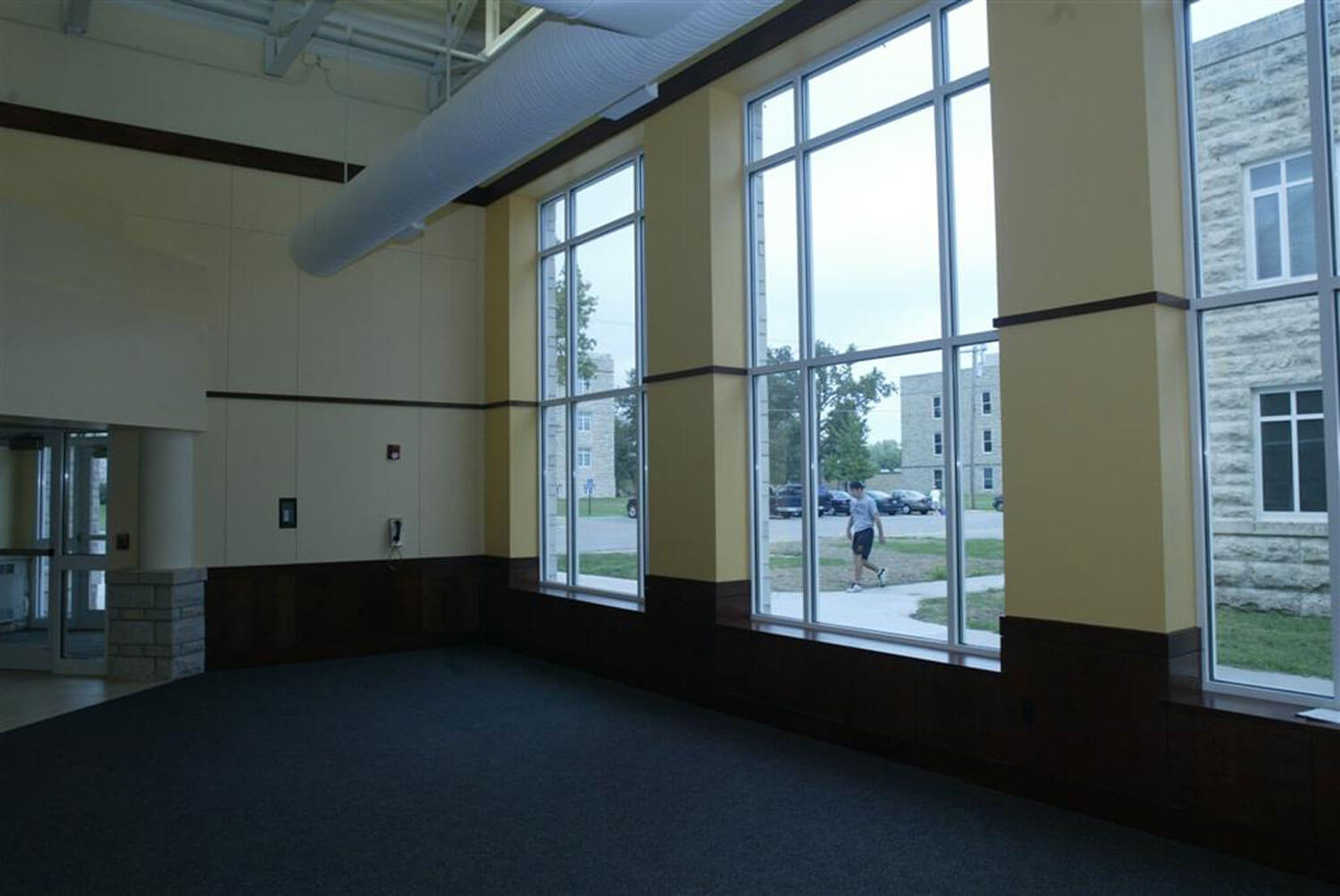 Open area near entrance on left, large windows to right, student walking outside