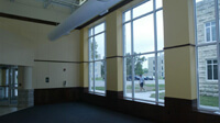 Open area near entrance on left, large windows to right, student walking outside